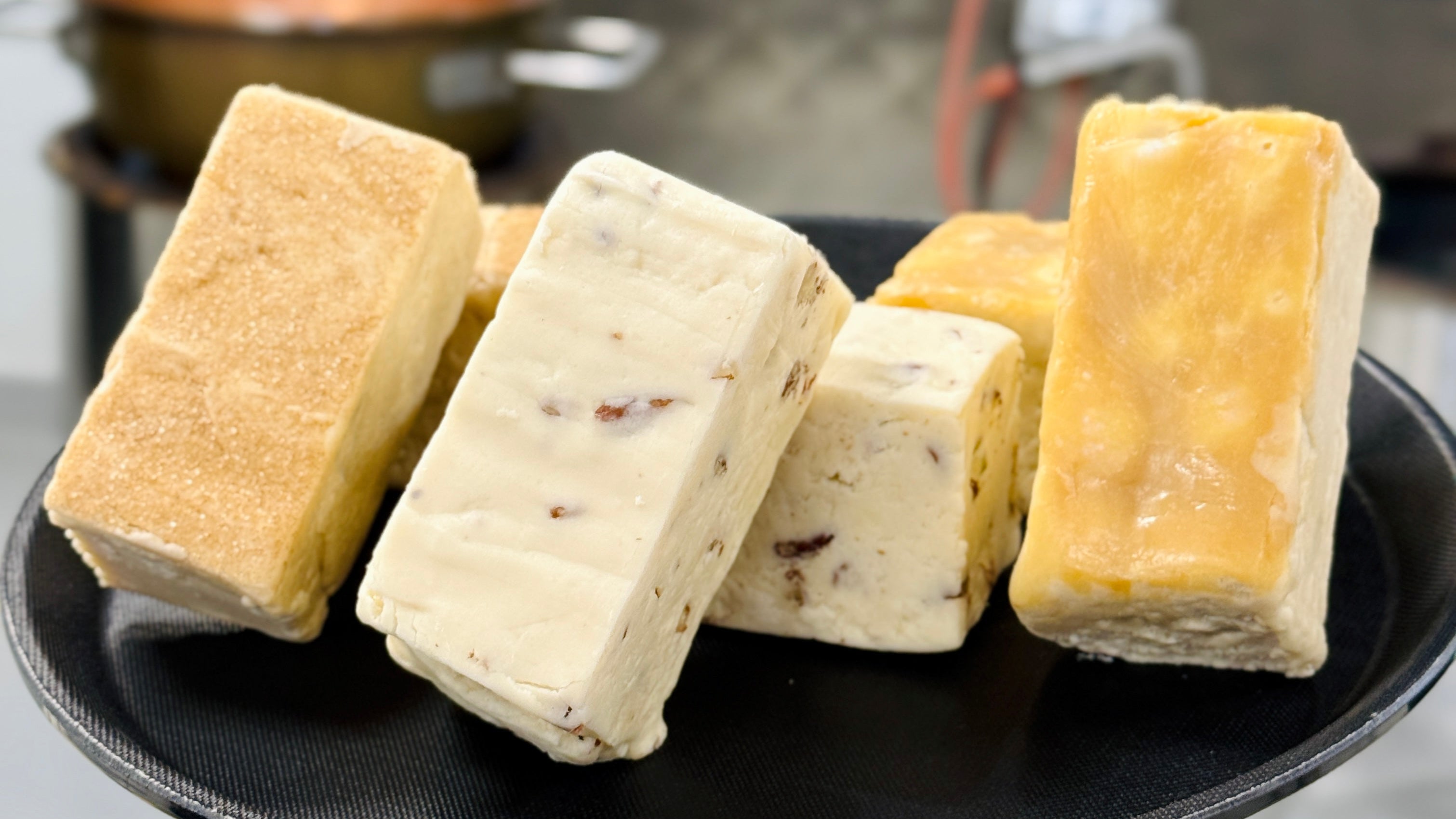 Blocks of fudge on a black plate with a blurred kitchen background