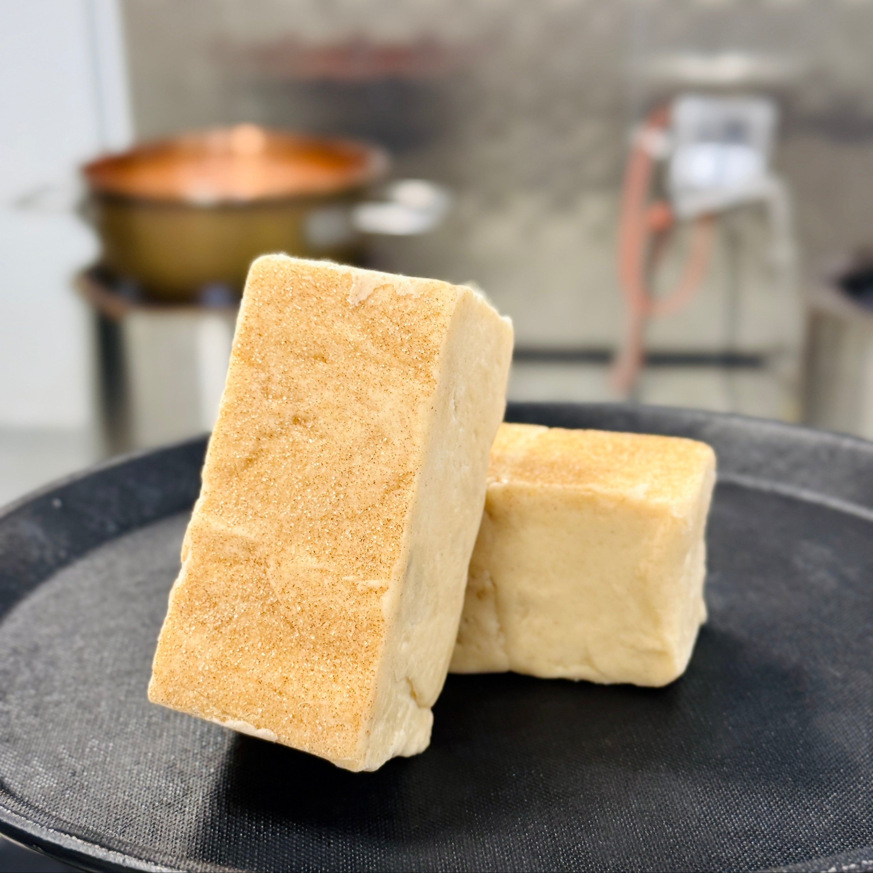 Two pieces of snickerdoodle fudge on a black plate with a kitchen background